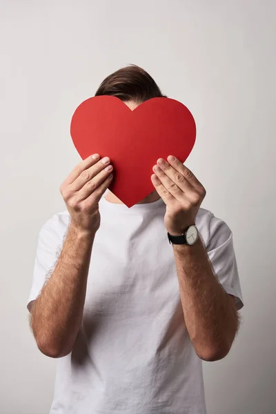 Hombre con cara oscura sosteniendo papel rojo vacío tarjeta de corazón cortado - foto de stock