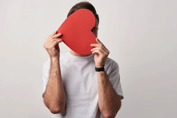 Mann versteckt Gesicht hinter leerem roten Papierschnitt Herzkarte isoliert auf grau — Stockfoto