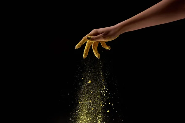 Cropped view of woman sprinkling yellow holi powder on black background — Stock Photo