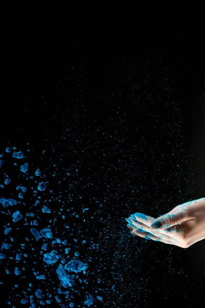 Vista recortada de la mujer adulta lanzando polvo de holi azul sobre fondo negro - foto de stock
