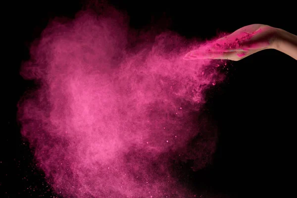 Vista ritagliata di donna adulta con polvere di oli rosa in aria su sfondo nero — Foto stock