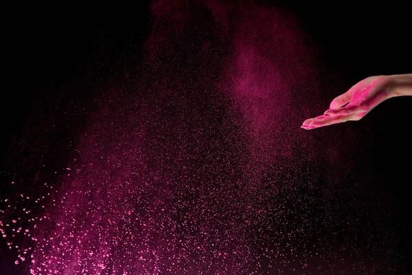 Vista ritagliata di donna adulta con polvere di oli rosa in aria su sfondo nero — Foto stock