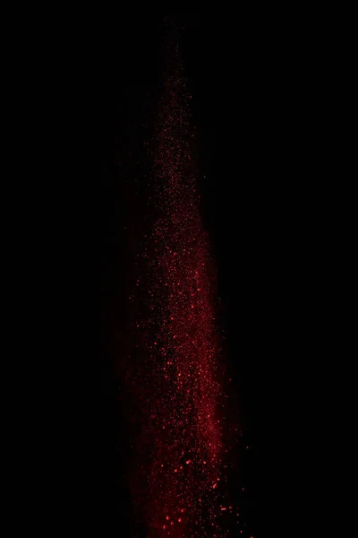Red powder in air and falling down on black background — Stock Photo