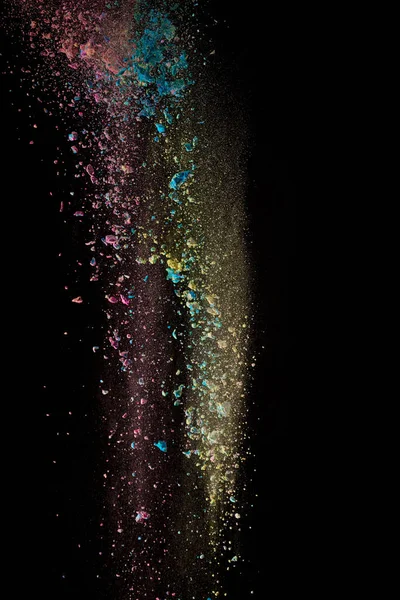 Red, yellow and blue powder in air on black background — Stock Photo