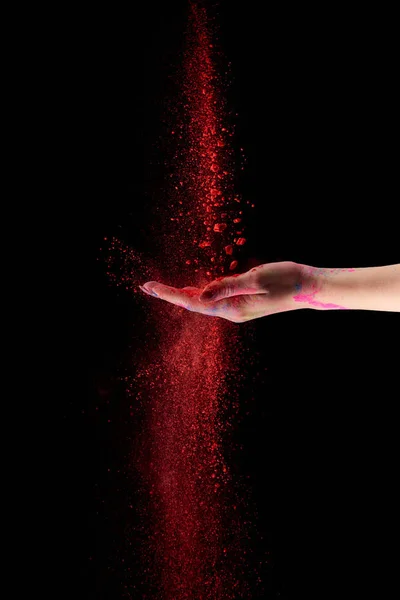 Vista recortada de la mujer adulta con polvo de holi rojo sobre fondo negro - foto de stock