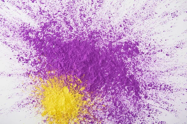 Top view of explosion of purple and yellow holi powder on white background — Stock Photo