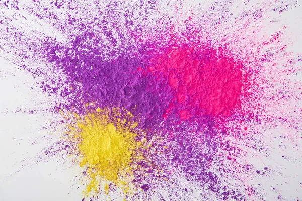 Vue de dessus de l'explosion de poudre holi violette, rose et jaune sur fond blanc — Photo de stock
