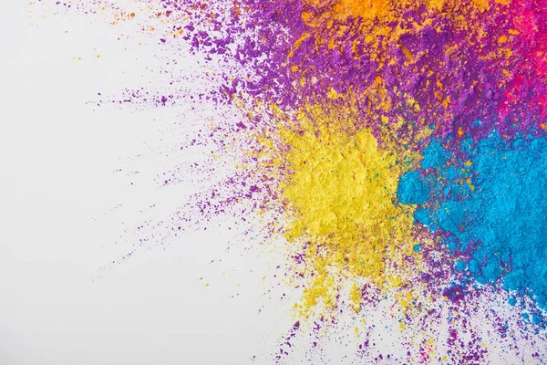 Draufsicht auf Explosion von gelbem, violettem, orangefarbenem und blauem Holi-Pulver auf weißem Hintergrund — Stockfoto