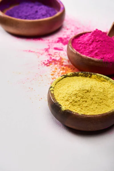 Holzschalen mit gelbem, rosa und lila Holi-Puder auf weißem Hintergrund — Stockfoto