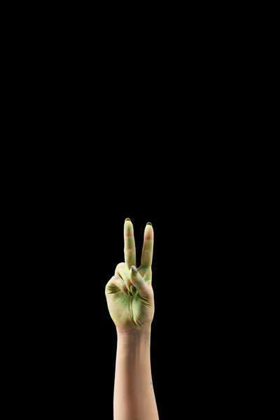 Cropped view of woman showing peace gesture in green holi powder isolated on black — Stock Photo