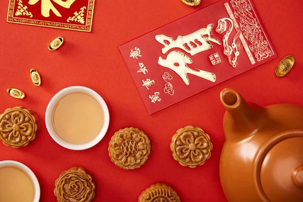 Draufsicht auf traditionelle Mondkuchen mit chinesischen Hieroglyphen und Tee isoliert auf Rot — Stockfoto