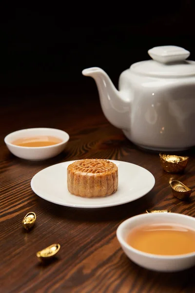Traditional mooncake with tea cups, pot and gold ingots isolated on black — Stock Photo
