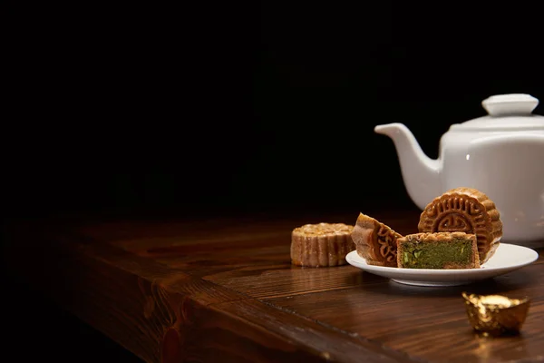 Tradicional chinês mooncakes, panela de chá e lingote de ouro na mesa de madeira isolada em preto com espaço de cópia — Fotografia de Stock
