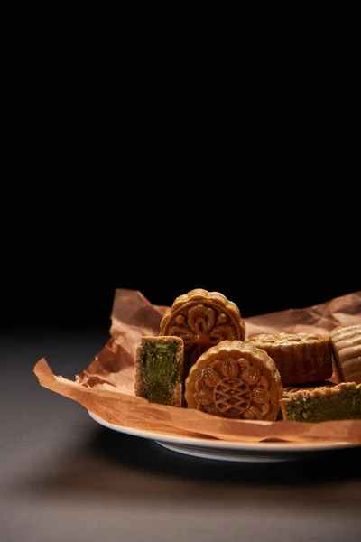 Traditional chinese mooncakes on plate isolated on black with copy space — Stock Photo