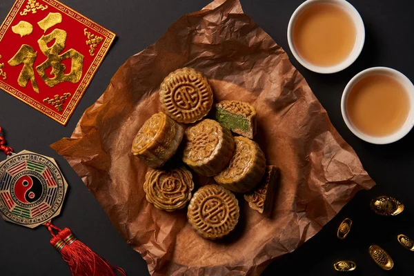 Top view of traditional mooncakes with chinese talismans and tea isolated on black — Stock Photo