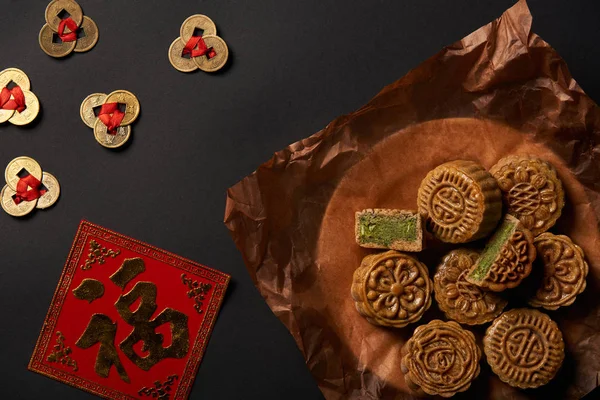 Vista superior de tortas de luna tradicionales con talismanes chinos aislados en negro - foto de stock