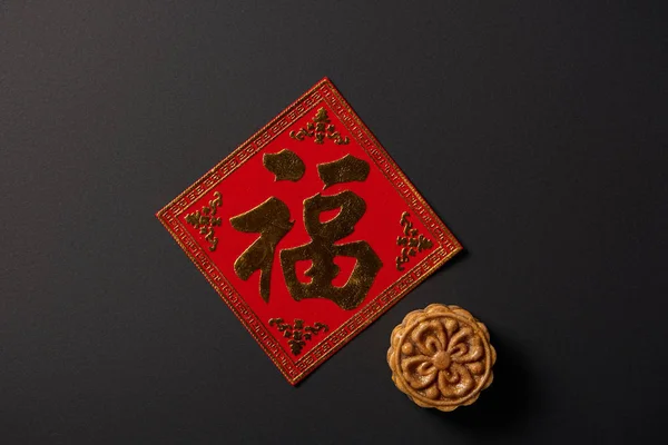 Vue de dessus du mooncake traditionnel et hiéroglyphe chinois isolé sur noir — Photo de stock
