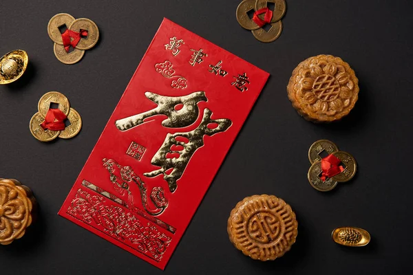 Вид на традиционные лунные кексы с китайскими иероглифами и монетами фэн-шуй, изолированными на черном — стоковое фото