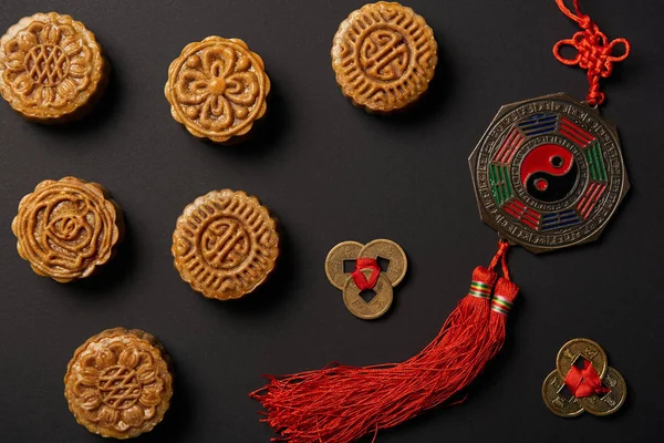 Vista superior de tortas de luna tradicionales con talismanes chinos aislados en negro - foto de stock
