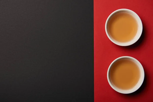 Vue du dessus des tasses à thé sur fond rouge et noir avec espace de copie — Photo de stock