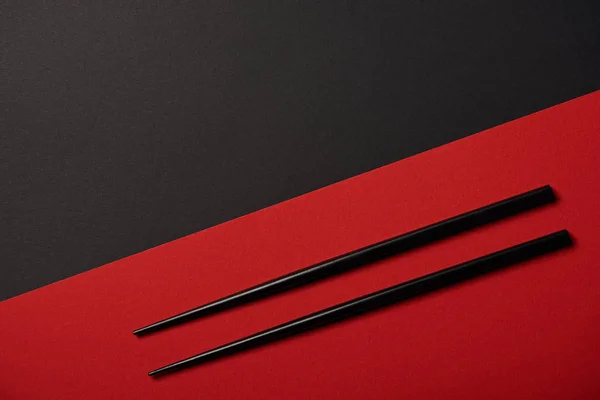 Top view of chopsticks on red and black background with copy space — Stock Photo