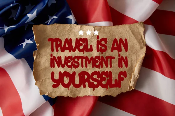 Papel arrugado vintage con viajes es una inversión en ti mismo cotización en bandera americana - foto de stock