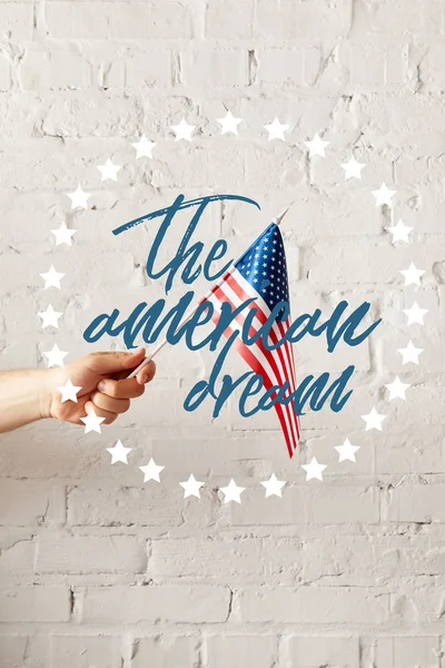 Cropped image of man holding american flagpole against white brick wall with the american dream illustration — Stock Photo