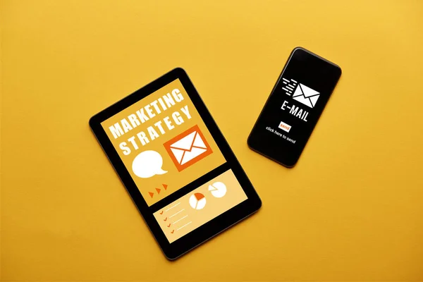 Top view of digital tablet and smartphone with marketing strategy and email apps on screen on yellow background — Stock Photo