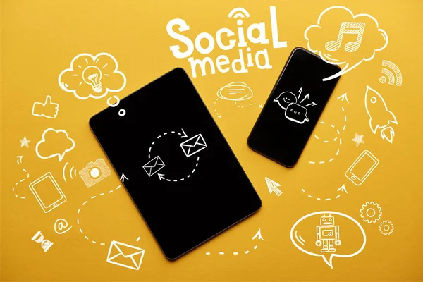 Vue du dessus de la tablette numérique et du smartphone avec l'illustration des médias sociaux sur fond jaune — Photo de stock