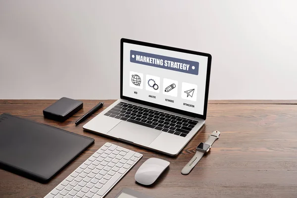 Плоский набор гаджетов и ноутбука с маркетинговой стратегии веб-сайт на экране на рабочем месте изолированы на серый — стоковое фото