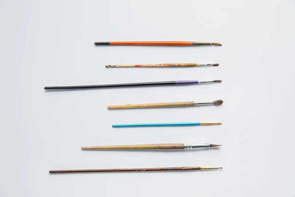 Top view of white background with paint brushes placed upright — Stock Photo