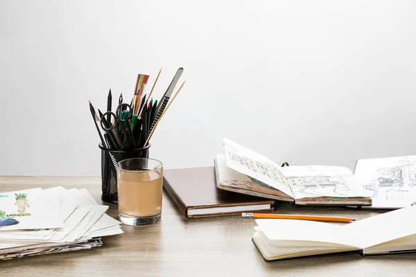 Mise au point sélective des albums de dessin, des ustensiles de dessin et du verre d'eau sur la table en bois — Photo de stock