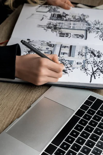 Foyer sélectif de femmes mains dessin dans l'album sur table en bois à côté de l'ordinateur portable — Photo de stock