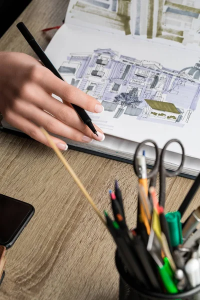 Selective focus of womans hands thumbing sketchbook on wooden table — Stock Photo