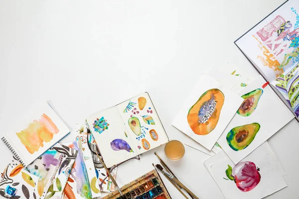 Top view of colorful watercolor paintings and drawing utensils — Stock Photo
