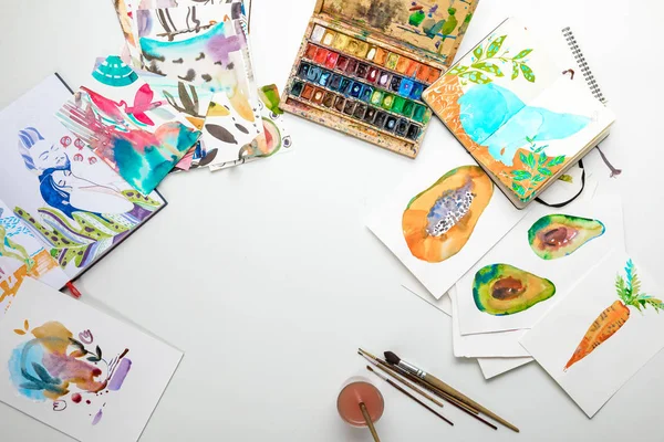 Top view of multicolored watercolor paintings and drawing utensils — Stock Photo