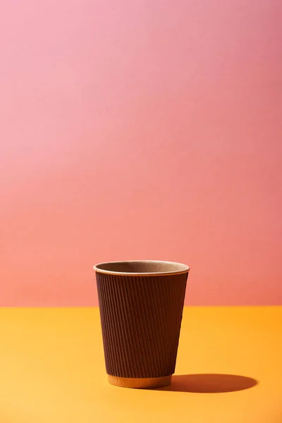 Tasse à café en papier sur fond jaune et rose — Stock Photo