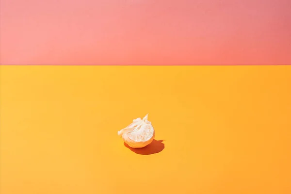 Frische Mandarinenscheiben auf gelber Oberfläche und rosa Hintergrund — Stockfoto