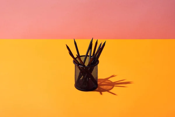 Pencil holder with pencils on yellow surface and pink background — Stock Photo