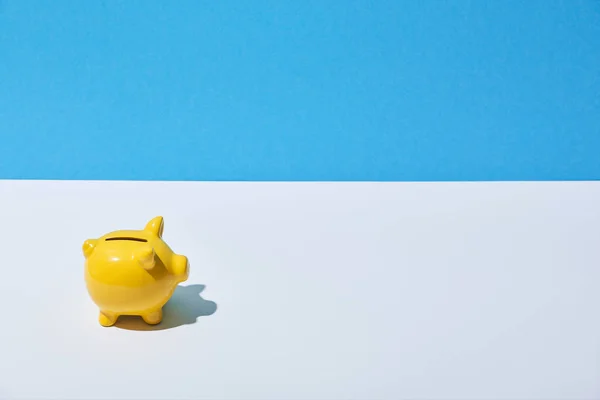 Banco piggy amarelo na mesa branca e fundo azul — Fotografia de Stock