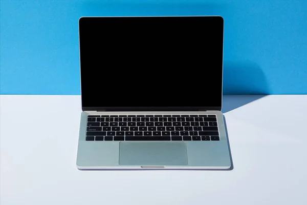 Laptop mit leerem Bildschirm auf weißem Schreibtisch und blauem Hintergrund — Stockfoto