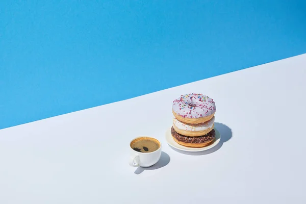 Leckere Donuts und Kaffeetasse auf weißem Schreibtisch und blauem Hintergrund — Stockfoto