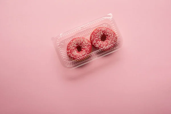 Vue de dessus des beignets glacés sucrés sur fond rose — Photo de stock