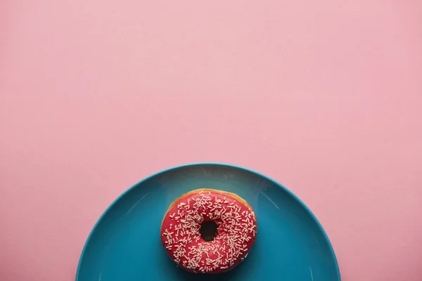 Draufsicht auf leckeren Donut auf blauem Teller isoliert auf rosa — Stockfoto