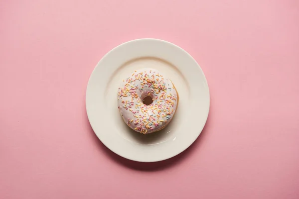 Vue du dessus de délicieux beignet sur plaque blanche sur fond rose — Photo de stock