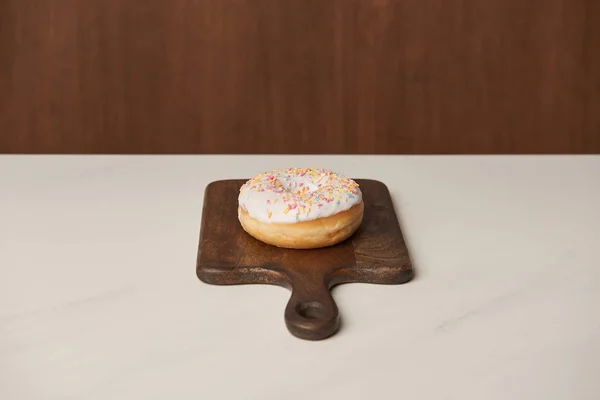 Delicious glazed donut on wooden cutting board — Stock Photo