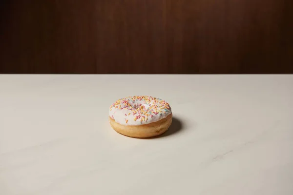 Tasty glazed doughnut with sprinkles on white table — Stock Photo