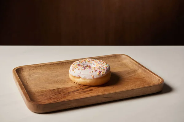 Saboroso donut com polvilhas na placa de corte de madeira — Fotografia de Stock