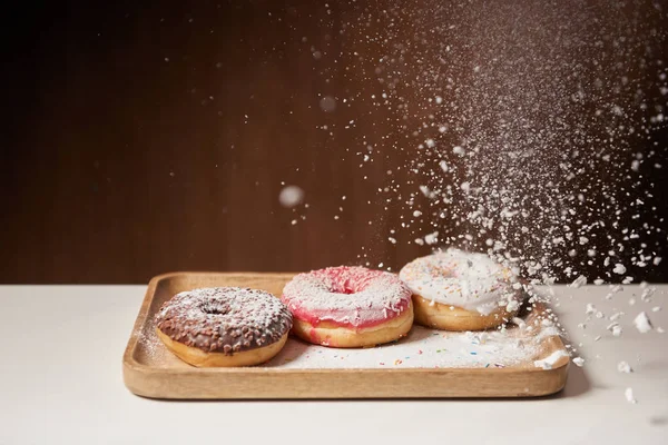 Donuts doces com peneiração de açúcar em pó em tábua de corte de madeira — Fotografia de Stock