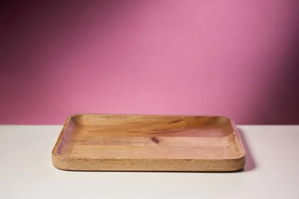 Wooden cutting board on white table on pink background — Stock Photo